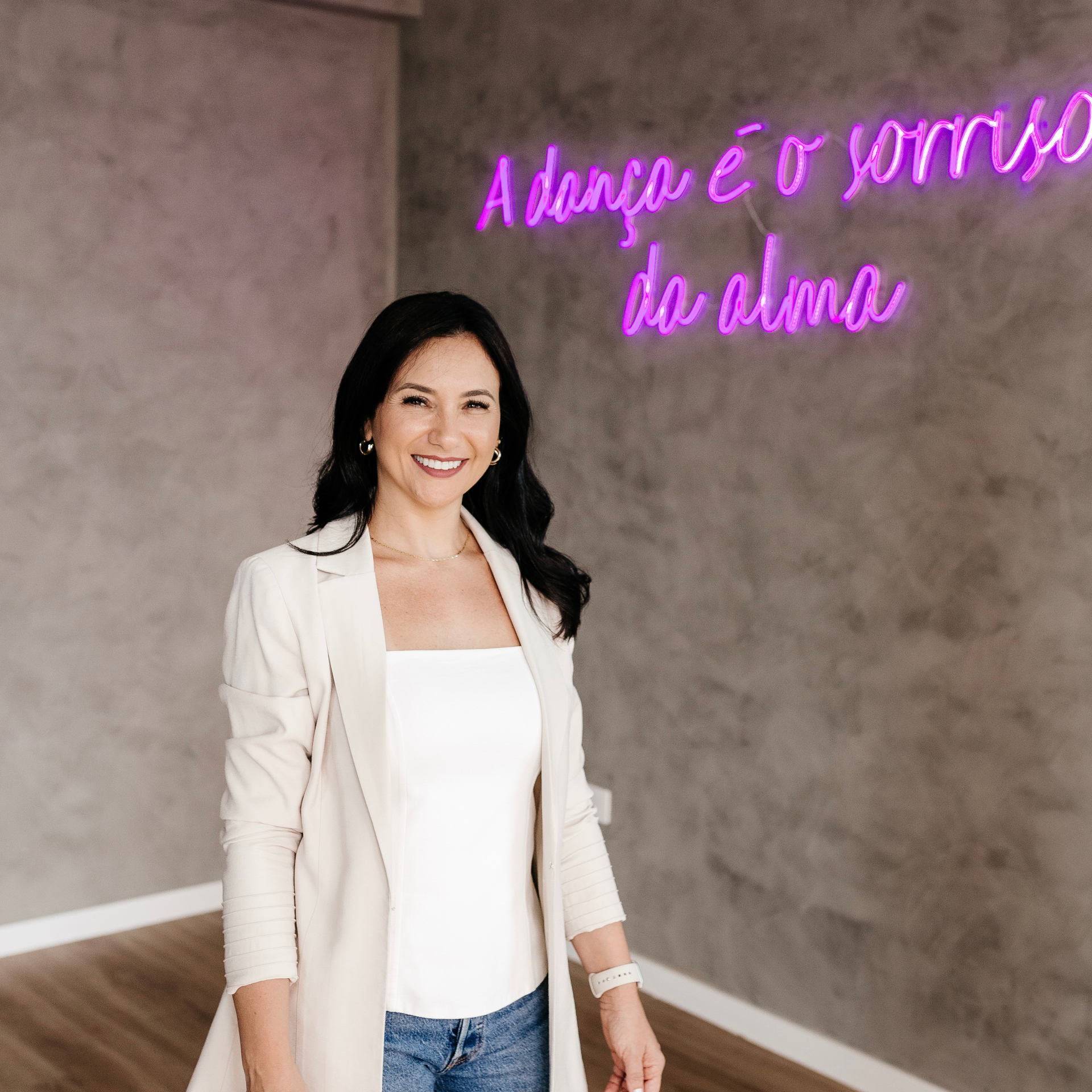 Retrato de Lilian Sanada em frente ao neon 'A dança é o sorriso da alma'